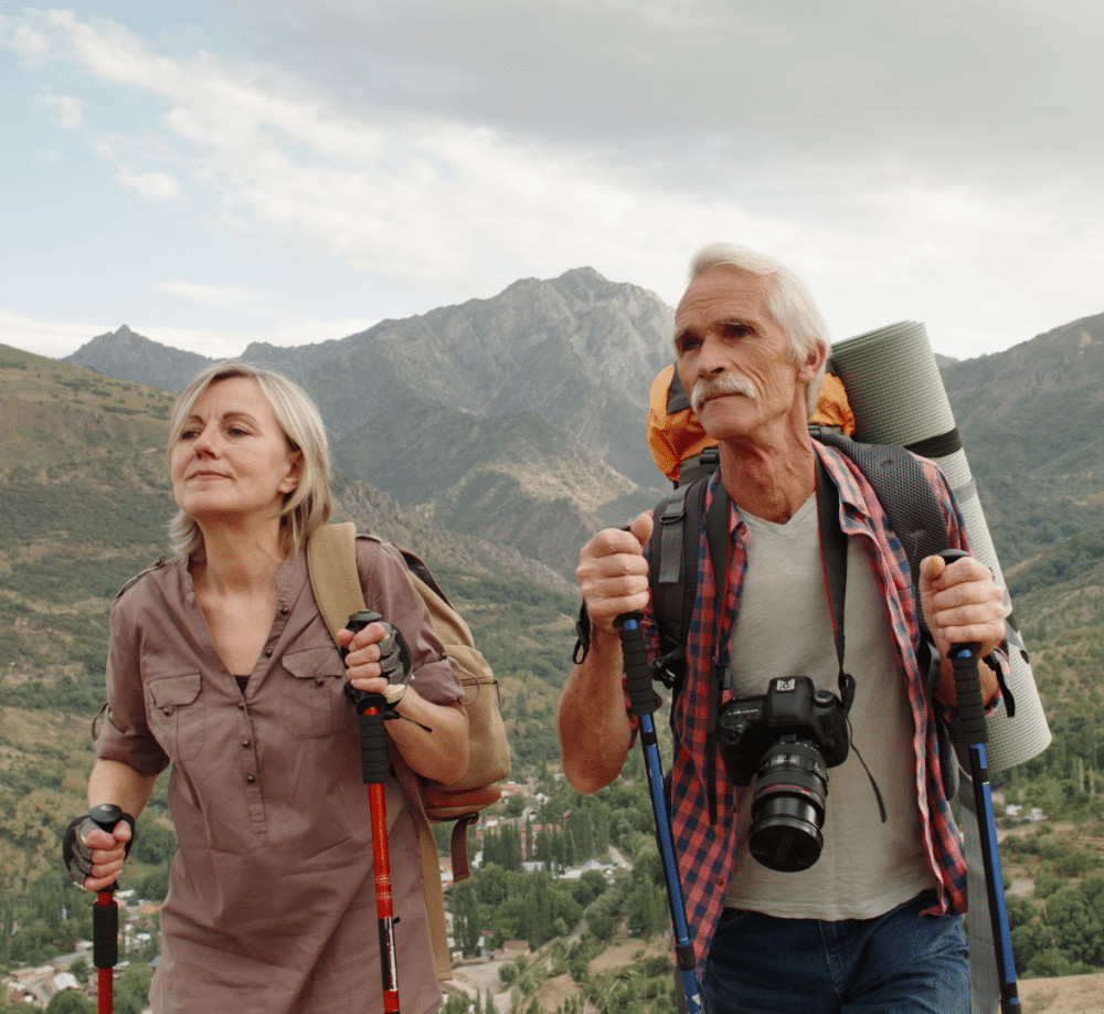 active senior caucasian couple hiking in mountains with backpacks enjoying their adventure 4k