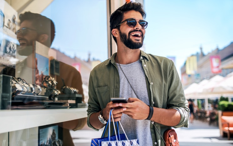 A man with shopping bags wearing sunglasses.