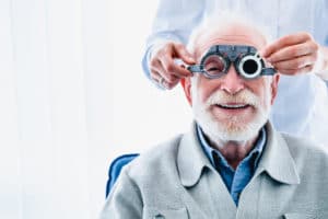 An older friendly bearded man smiles as he receives an eye exam