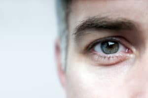 A close up of the side of a man's face zoomed in to show his eye, eyebrow, ear and the top of his cheek