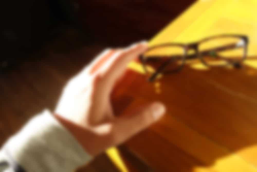 An upclose image of a man reaching for his glasses with blurry vision