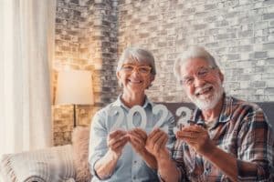 couple of two old pensioners holding together numbers of 2023 at home