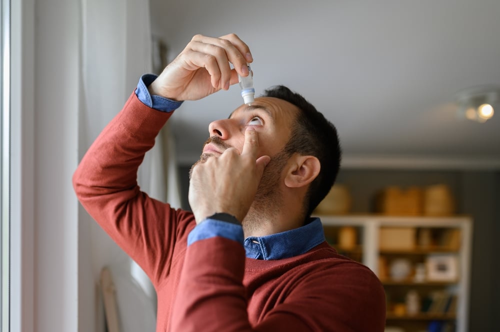 A man putting drops in his eyes to treat glaucoma