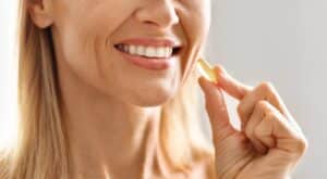 Woman is about to swallow a vitamin supplement to improve her ocular health and diminish dry eye symptoms.