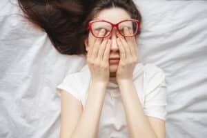 Woman laying down rubbing eyes due to diabetic retinopathy symptoms in Loveland, CO