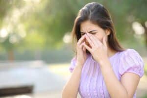 Woman outdoors holding her eyes due to dry eye syndrome symptoms in Loveland, CO