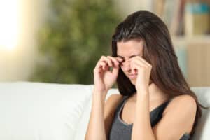Woman rubbing her eyes with herpes simplex eye infection in Loveland, CO