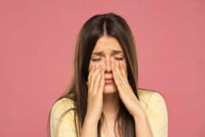 Woman holding her eyes in discomfort due to dry eye or another condition in Loveland, CO