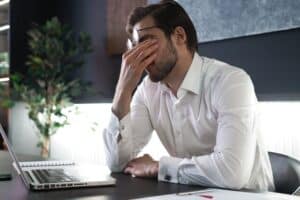 Man at his desk rubbing his eyes because of retinal tear in Loveland, CO