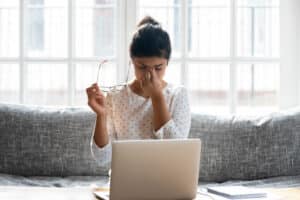 Woman at computer holding eyes due to dry eye in Loveland, CO